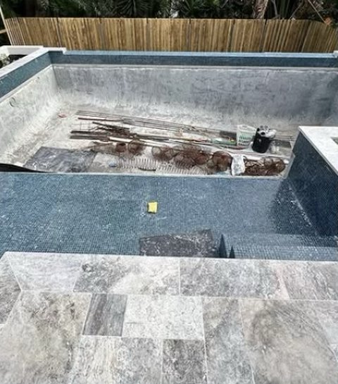 Pool with dark mosaic tiles and stone coping